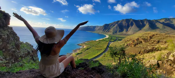 Woman with hat, arms outstretched, on a cliff overlooking a blue ocean, beach, and mountains. Imagine this rv rental adventure!. Ford E250 2009