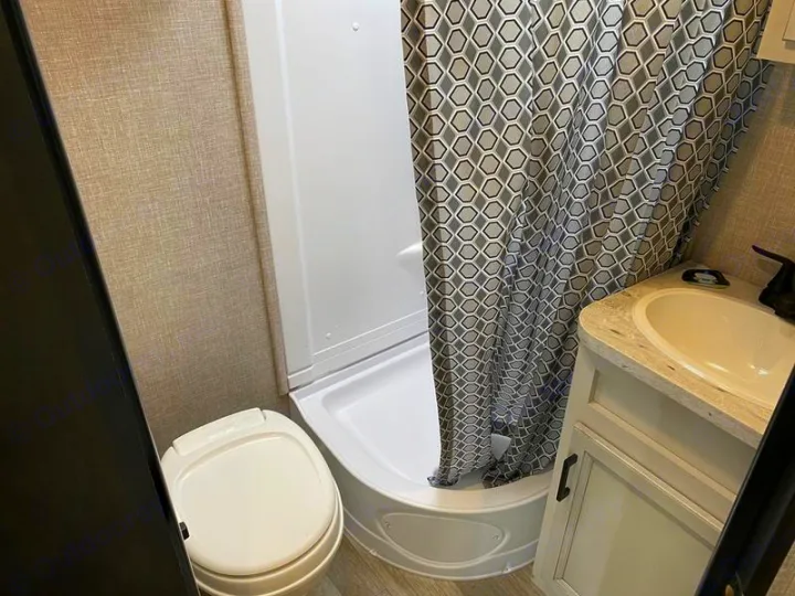 RV rental bathroom featuring a compact toilet, shower with patterned curtain, and a sink vanity.. Jayco 166 FBS 2022
