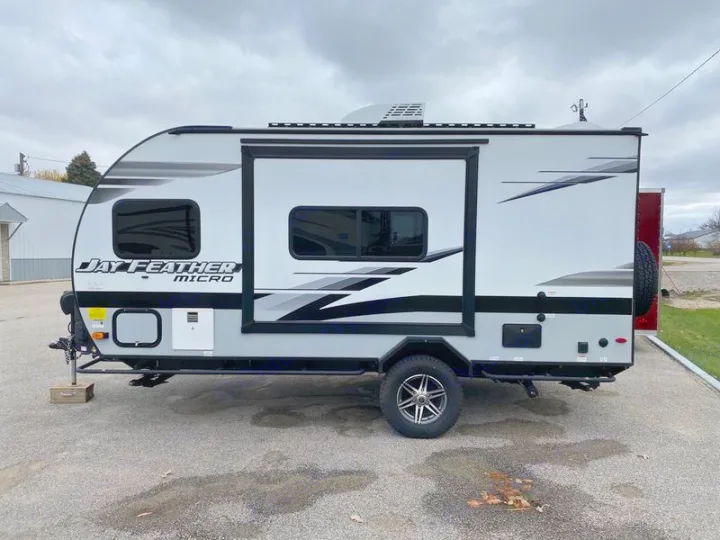 Sleek, compact grey & white Jay Feather Micro travel trailer RV, ideal for an rv rental adventure. Parked outdoors on asphalt.. Jayco 166 FBS 2022