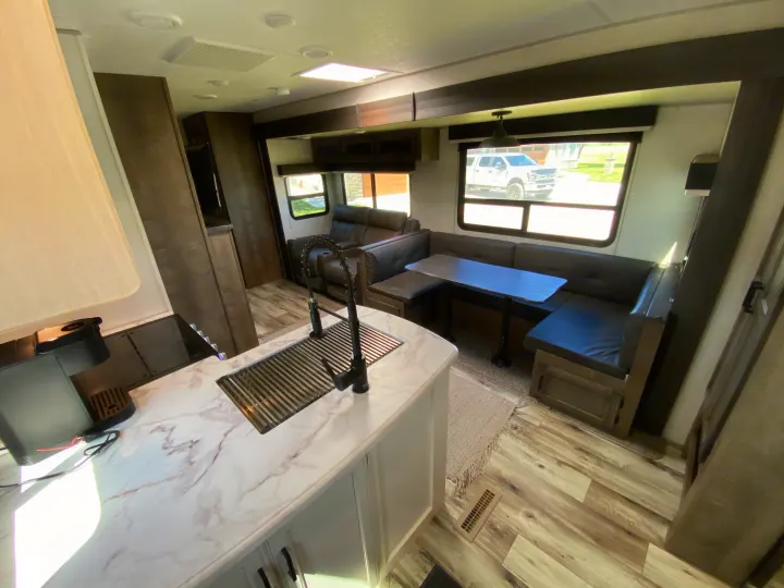 Modern RV rental interior with kitchen island, spacious dinette, and comfortable recliners for a relaxing journey.. Venture Sporttrek 2022