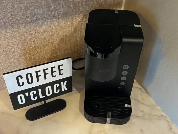 A black Keurig coffee maker and 'Coffee O'Clock' sign on a marble-patterned counter, ideal for an RV rental.. Jayco 21MML 2023
