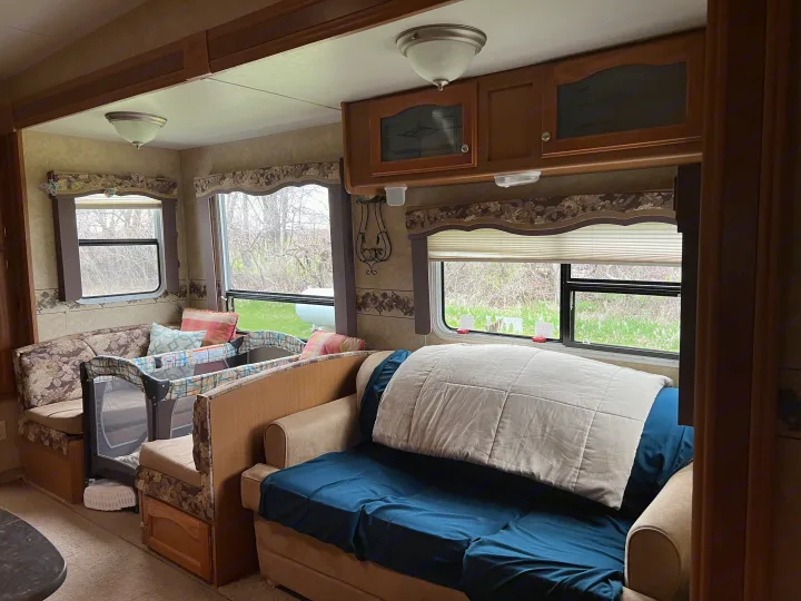 Cozy RV rental interior featuring a sofa, dinette, and a pack-n-play, perfect for family travel.. Denali Denali Fifth Wheel 2011