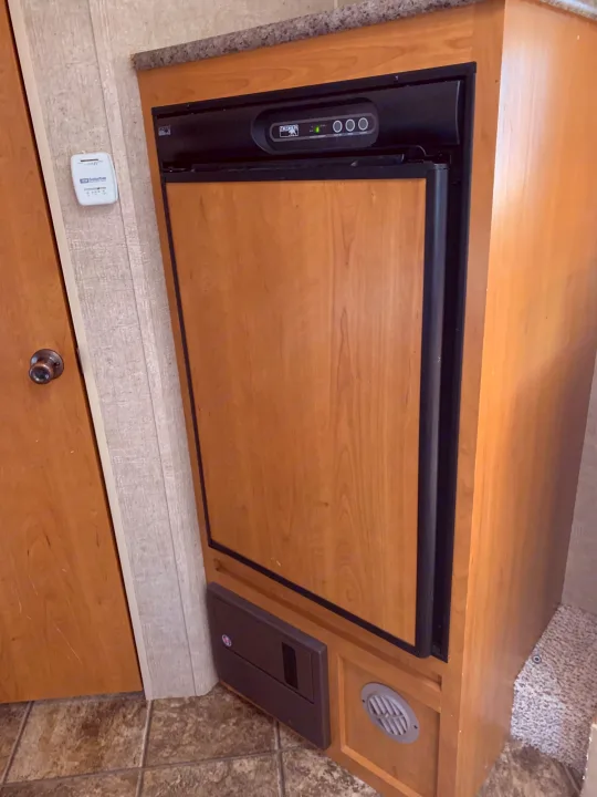 Inside an RV rental: a Norcold refrigerator, Suburban thermostat, and electrical panel in the compact living area.. Escape Trailer Industries Escape 5.0ta 2013