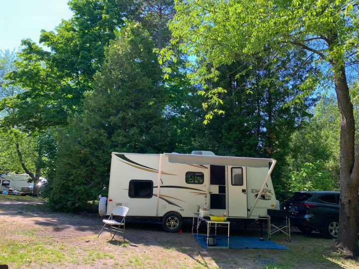 Enjoy your outdoor escape! This RV rental is set up at a shaded campsite with an awning, chairs, and table ready for use.. Escape Trailer Industries Escape 5.0ta 2013