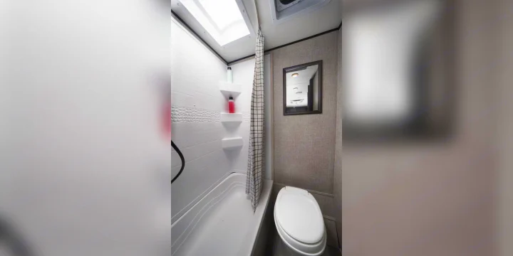 Step inside this clean RV rental bathroom, featuring a compact shower, toilet, skylight, and convenient shelves. Perfect for travel!. Jayco Jay Flight 2023