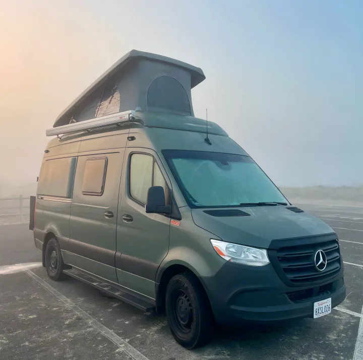 Green Mercedes-Benz Sprinter camper van, an ideal RV rental, parked in a foggy outdoor lot.. Mercedes-Benz Sprinter “144” 2020