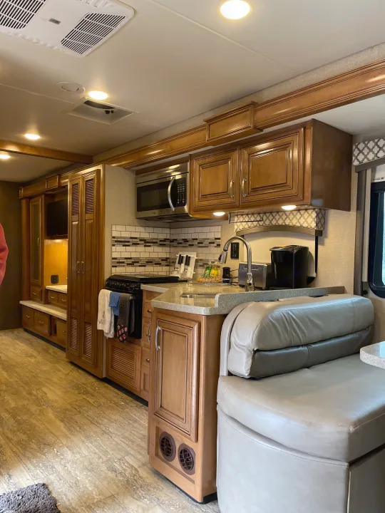 Well-appointed rv rental interior with a kitchen, dining booth, wood-look floors, and built-in storage.. Thor Chateau 2018