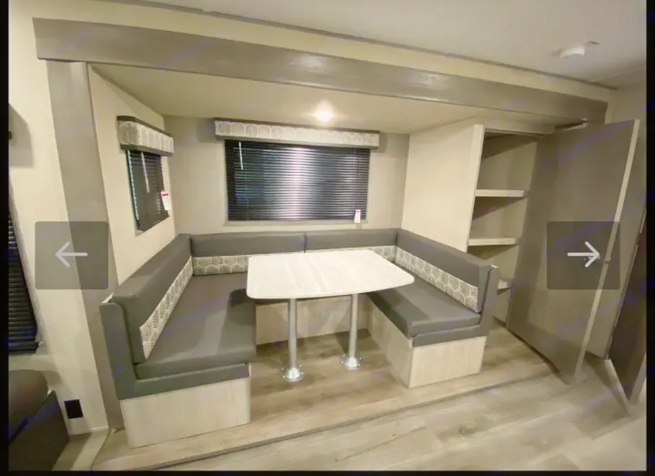 This rv rental's dinette features U-shaped bench seating, a table, window blinds, and open storage shelves.. Coachmen Summit series 2023