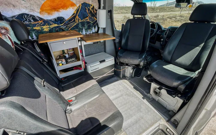 Step inside this RV rental! A custom camper van interior with practical storage, Dometic cooler, and swivel seats for adventure.. Mercedes-Benz Sprinter 2016