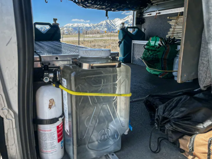 Inside an RV rental: water jug, fire extinguisher, and smart storage, overlooking scenic snow-capped mountains.. Mercedes-Benz Sprinter 2016