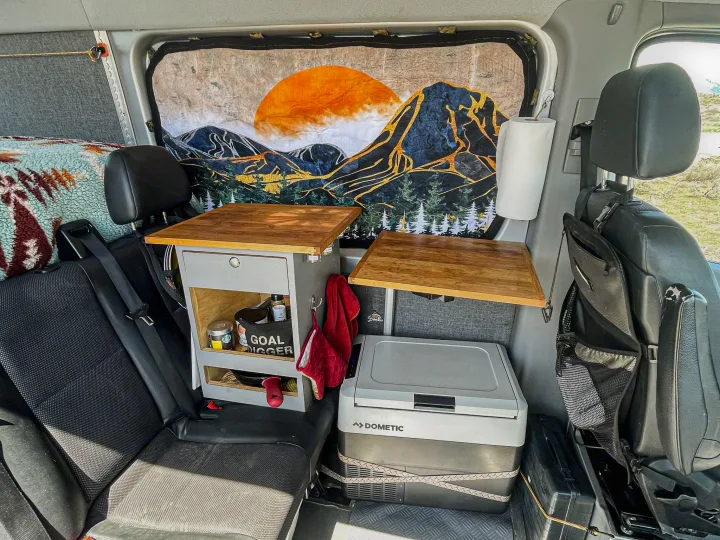 RV rental interior featuring custom storage with pull-out tables, a Dometic fridge, and a scenic mountain mural.. Mercedes-Benz Sprinter 2016