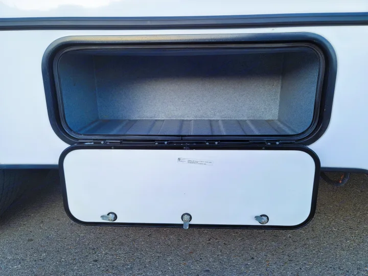 Open exterior storage compartment of an RV, ready for gear on your rv rental trip. Empty interior, visible door latches.. Forest River Sunseeker LE 2022