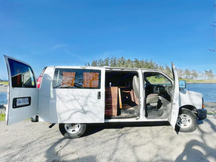 White converted van, doors open, parked by water. A great option for an RV rental & road trip adventure.. Chevrolet Other 2009