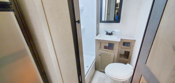 Functional and compact RV rental bathroom featuring a shower, sink, and toilet. Ideal for road trips!. Forest River Surveyor Legend 2022