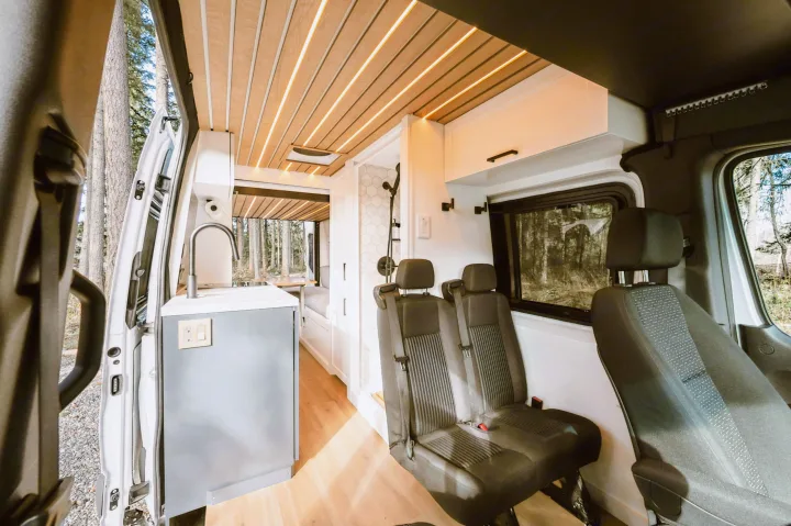 This modern RV rental features a compact kitchen, sleek wood ceiling, rear seating, and a shower, ideal for travel.. Mercedes-Benz Sprinter 2021