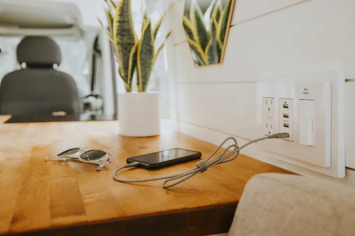 Stay powered on your RV rental adventure! Modern RV interior with a phone charging on a wooden counter, next to sunglasses & a plant.. Ram Promaster 2500 2019