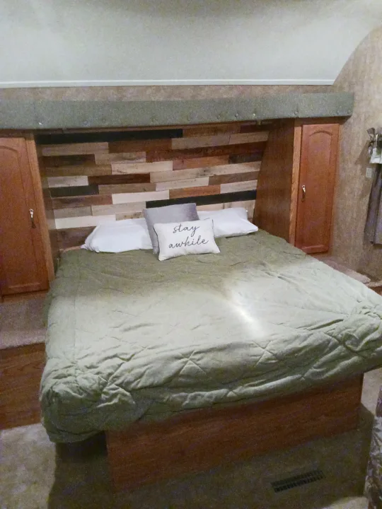 Cozy RV rental bedroom: comfy bed, wood-plank headboard, built-in storage units for travelers.. Timberland Wedge 2008