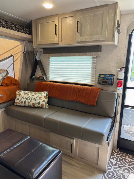 Spacious RV rental living area featuring comfortable seating, overhead cabinets, and a cozy pop-out bed.. Forest River Flagstaff Shamrock 2022