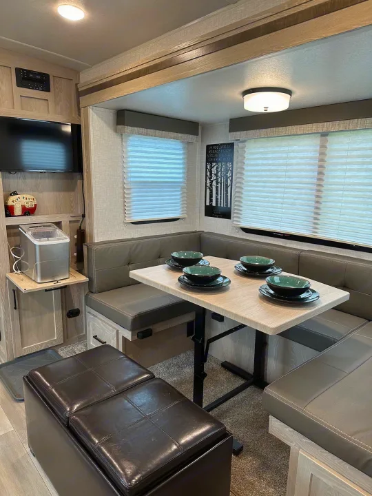 Explore this RV rental's inviting interior: a fully-equipped dinette with comfortable seating, TV, and ice maker.. Forest River Flagstaff Shamrock 2022