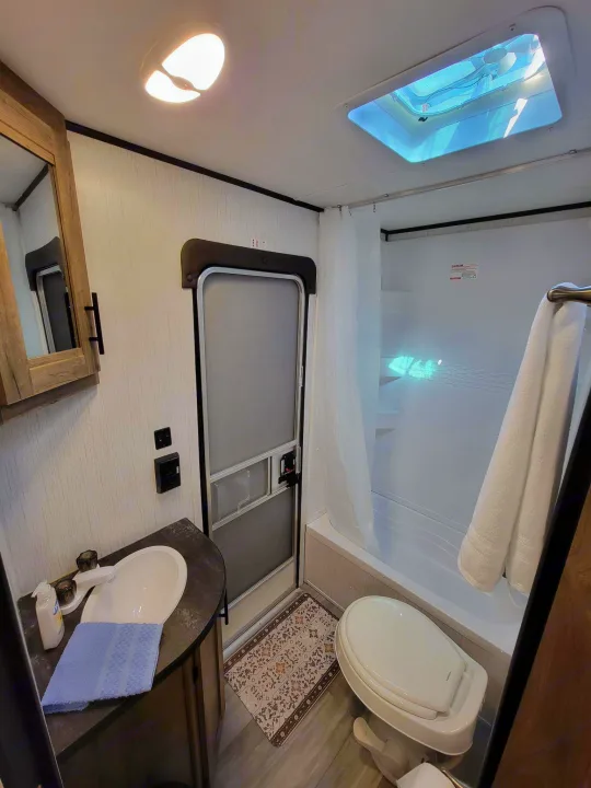 Modern RV rental bathroom showcasing a practical layout with vanity, sink, toilet, shower, and skylight. Ready for your trip!. Heartland RVs Pioneer 2021