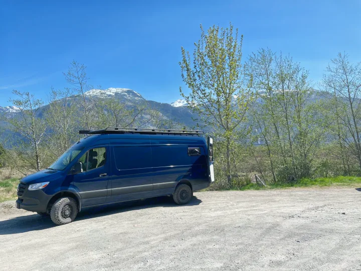 Dark blue Sprinter camper van on a gravel road, mountains in background. Perfect for your next RV rental adventure!. Mercedes Sprinter 2022