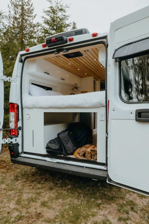 Spacious RV rental interior featuring a cozy bed, ample storage for travel gear & firewood. Perfect for adventure!. Ram Promaster 2500 2021