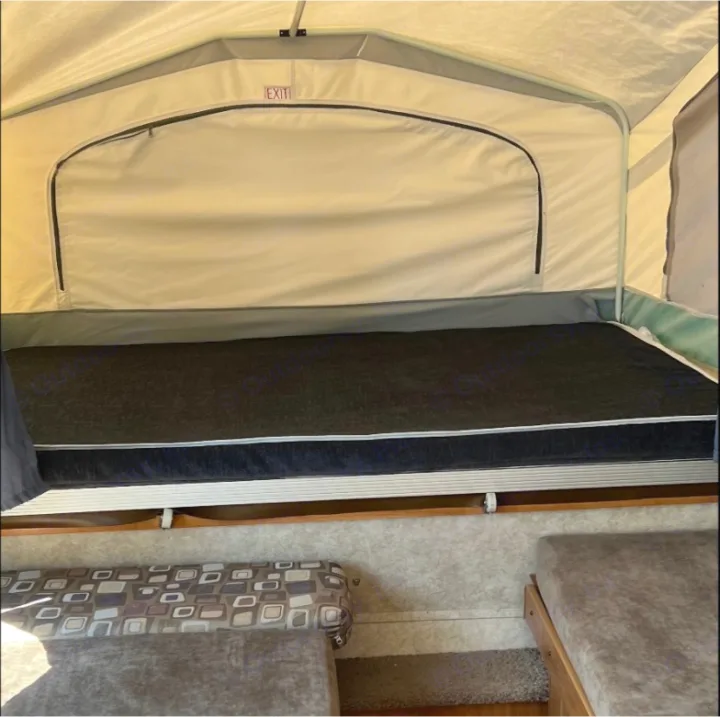 Pop-up RV rental interior: a comfy bed with black mattress & an 'EXIT' sign above.. Forest River Palomino 2010