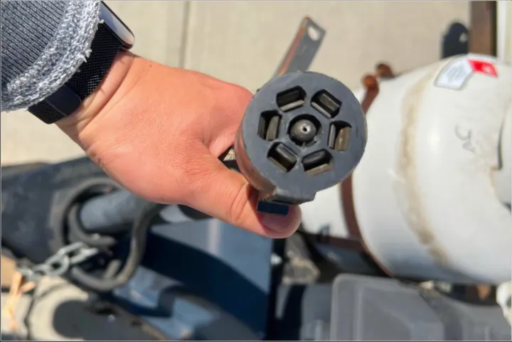 Hand holds a 7-pin trailer connector for RV rental electrical hookup, vital for safe towing.. Forest River Palomino 2010