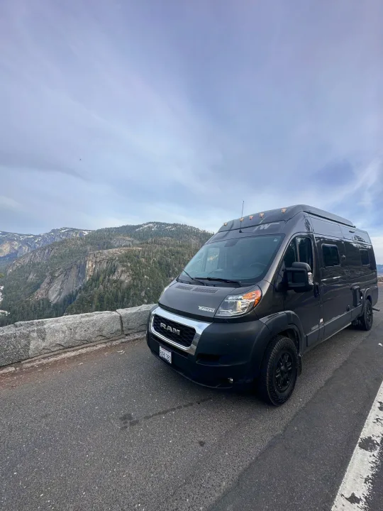 Dark gray Winnebago rv rental parked at a scenic mountain overlook, offering stunning valley views.. Winnebago Solis 2022