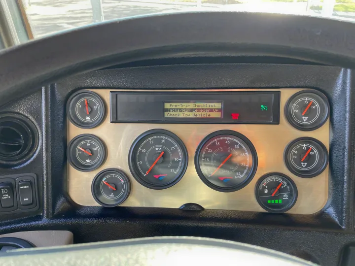 **RV rental** dashboard view, featuring various gauges and a digital display with a pre-trip checklist and "PARKING BRAKE" warning.. Fleetwood Excursion 2015