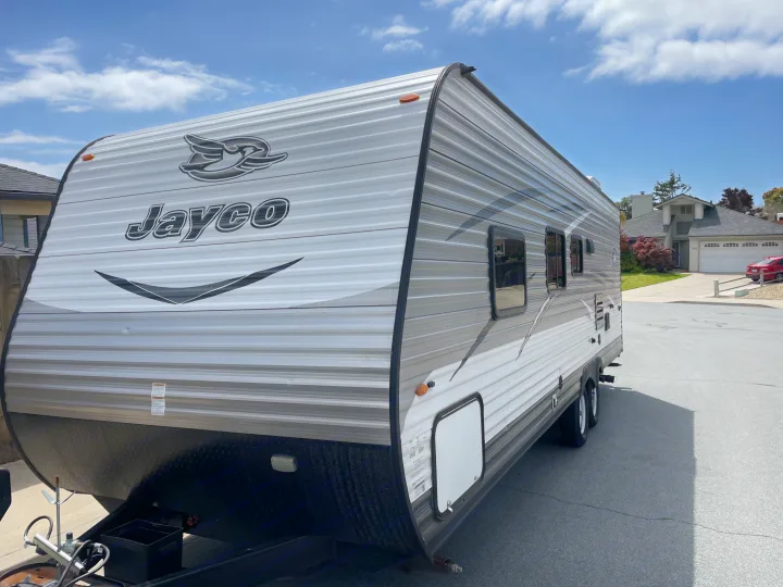This Jayco RV travel trailer, with its distinctive gray & white design, is parked outdoors and ready for rv rental.. Jayco Jaycoflight 2017