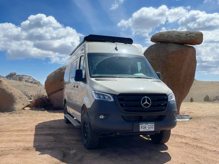 A light Mercedes Sprinter RV rental, perfect for off-road adventures, parked among massive Colorado boulders under a blue sky.. Winnebago Revel 2022