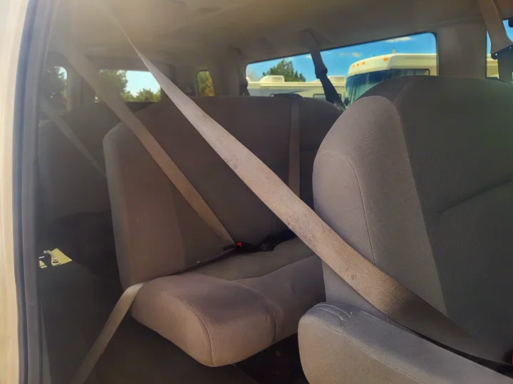 Interior view of an RV rental, featuring gray rear seats and seatbelts, with other RVs parked outside.. Ford Ford E350 2009