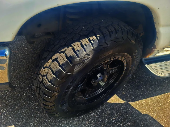 Front wheel of an RV rental vehicle, with a rugged Nokian Outpost AT tire on a black Ultra Motorsports rim. Parked on asphalt.. Ford Ford E350 2009