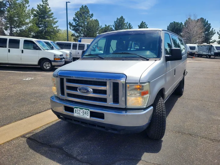 Silver Colorado Ford van at an RV rental lot, with other vans and RVs visible in the background.. Ford Ford E350 2009