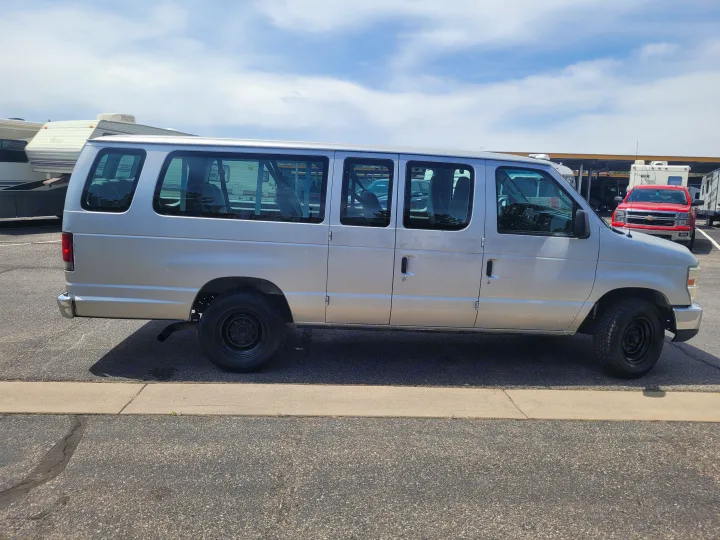Silver passenger van parked among other vehicles, including RVs.. Ford Ford E350 2009