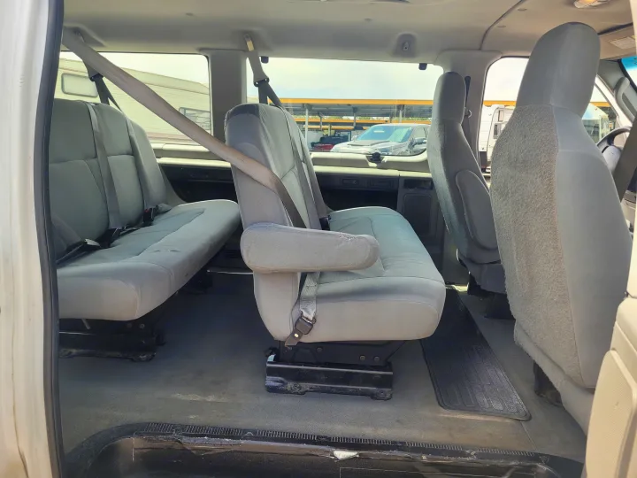Interior view of a passenger van for RV rental, showing grey multi-row seating with seatbelts.. Ford Ford E350 2009