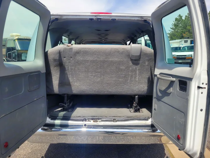 Open rear of a white van, showing a gray bench seat and spacious interior. Ideal for an RV rental conversion or transport.. Ford Ford E350 2009