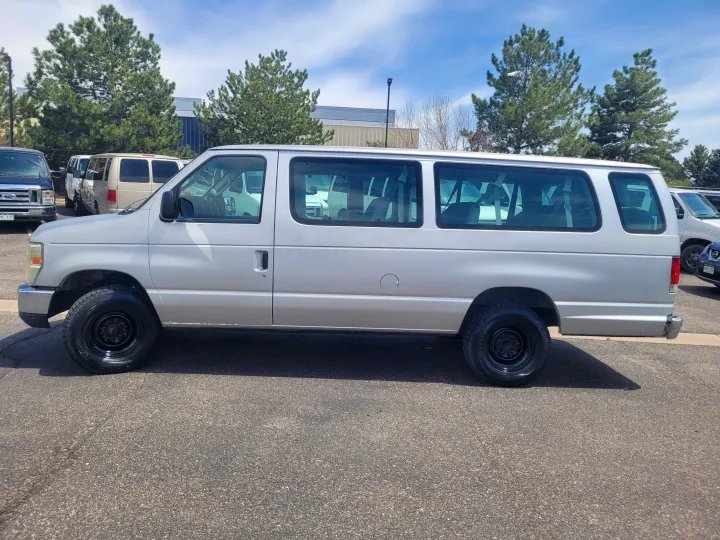 Side view of a silver multi-passenger van, seen in a parking lot. This type is often used for group travel or as an RV rental.. Ford Ford E350 2009