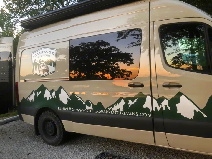 Customized adventure van for RV rental, featuring a mountain decal & sunset reflected in the window.. Mercedes-Benz Sprinter 2023