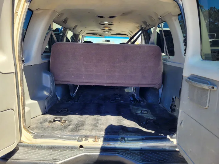 Rear interior of an RV rental van, showing the back bench seat and versatile floor for cargo/seating.. Ford E-350 2007