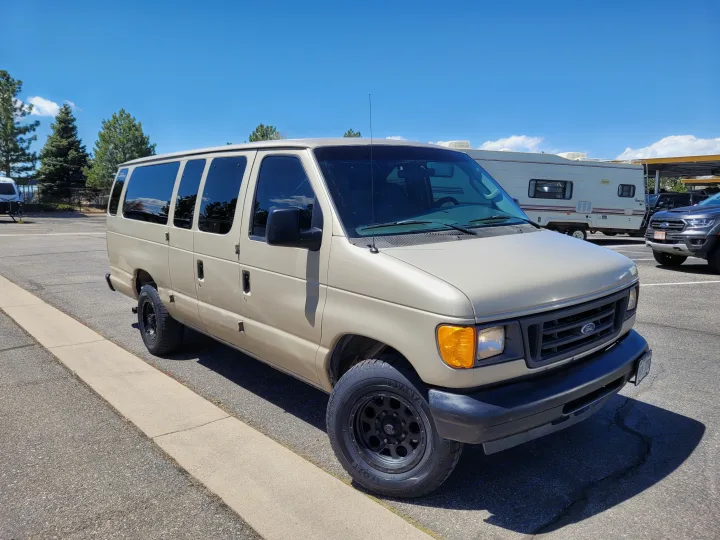 Tan Ford van and a white RV in a sunny lot. Explore rv rental possibilities in this vibrant setting!. Ford E-350 2007
