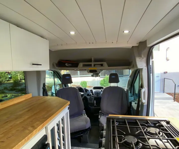 Modern rv rental camper van interior with kitchen, wood ceiling, and driver/passenger seats visible.. Ford Transit Custom 2015