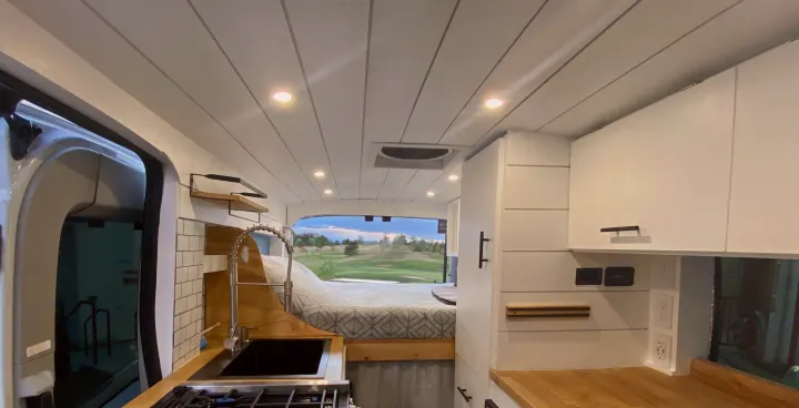Explore this RV rental: bright interior, complete kitchen with sink/stove, comfortable bed, and panoramic golf course views.. Ford Transit Custom 2015