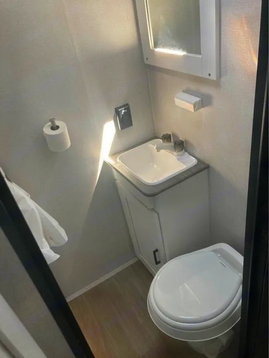 Inside an RV rental, this compact bathroom features a toilet, sink, and mirror. Efficient design for travel.. Keystone RV Hideout 2022