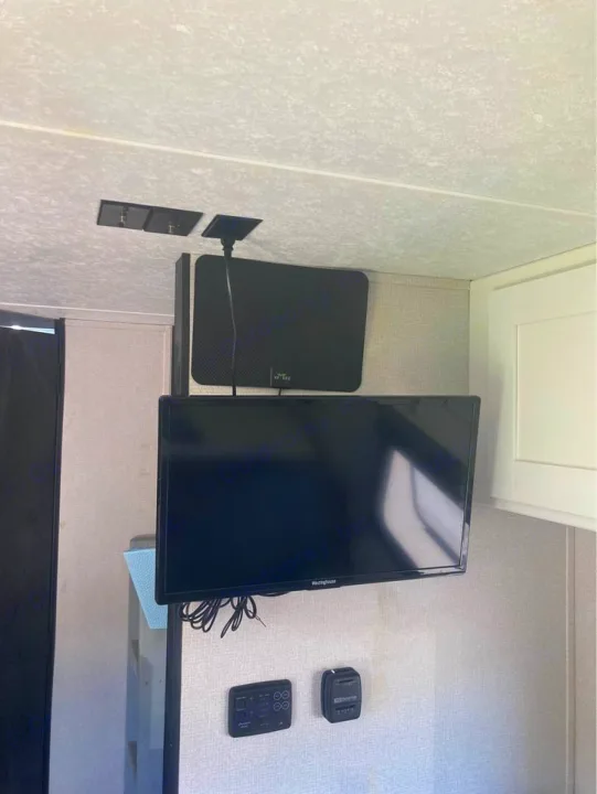 RV rental interior: wall-mounted TV & flat antenna for entertainment, with climate control panels below.. Keystone RV Hideout 2022