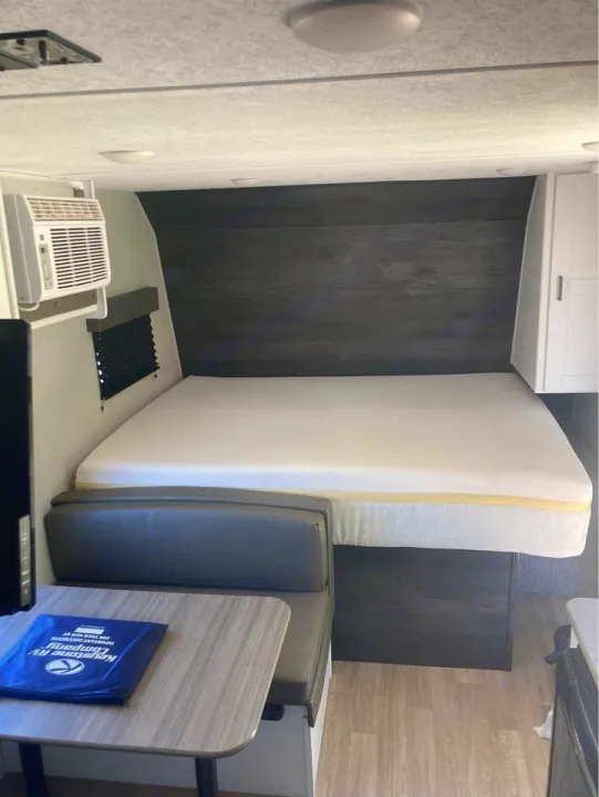 Cozy RV rental interior showing a bed, dinette, and AC unit. Perfect for travel adventures!. Keystone RV Hideout 2022