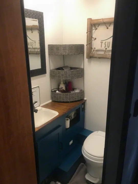 This compact RV rental bathroom includes a sink, toilet, blue vanity, and clever woven storage shelves.. Other Other 2008