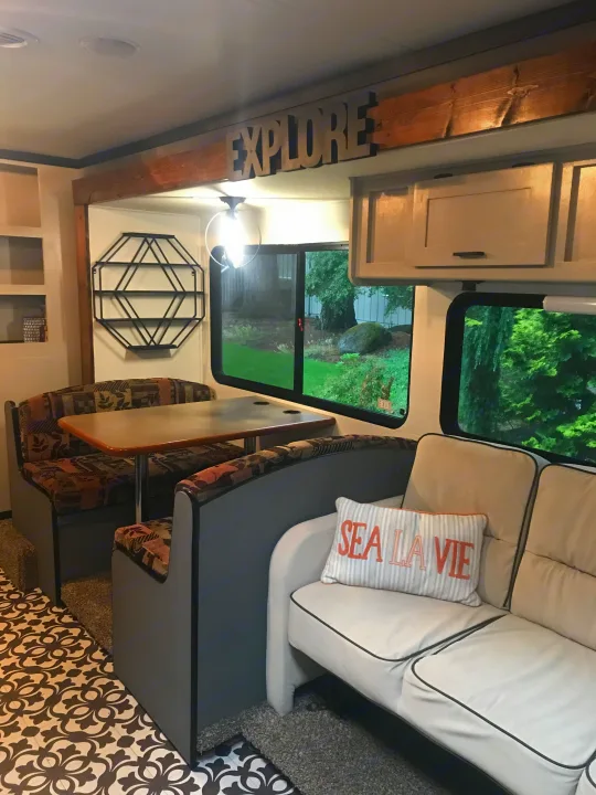 Cozy RV rental interior with dining booth, comfy sofa, scenic window view, and an "EXPLORE" sign for adventure.. Other Other 2008