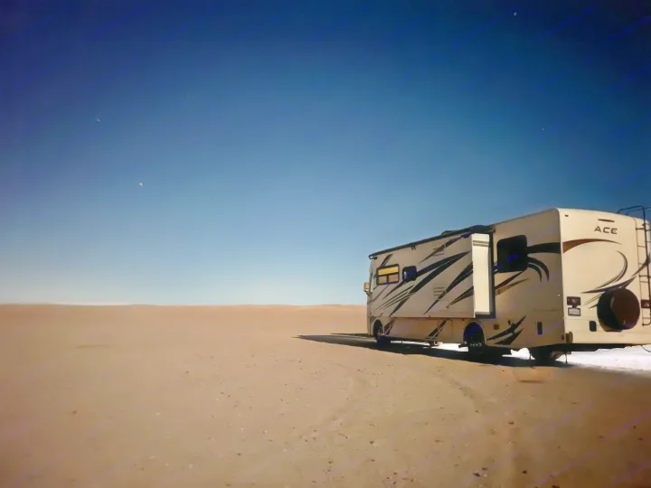 An RV rental parked under a clear, starry night sky in a vast, sandy desert landscape, ideal for remote camping.. Thor Motor Coach A.C.E 2020